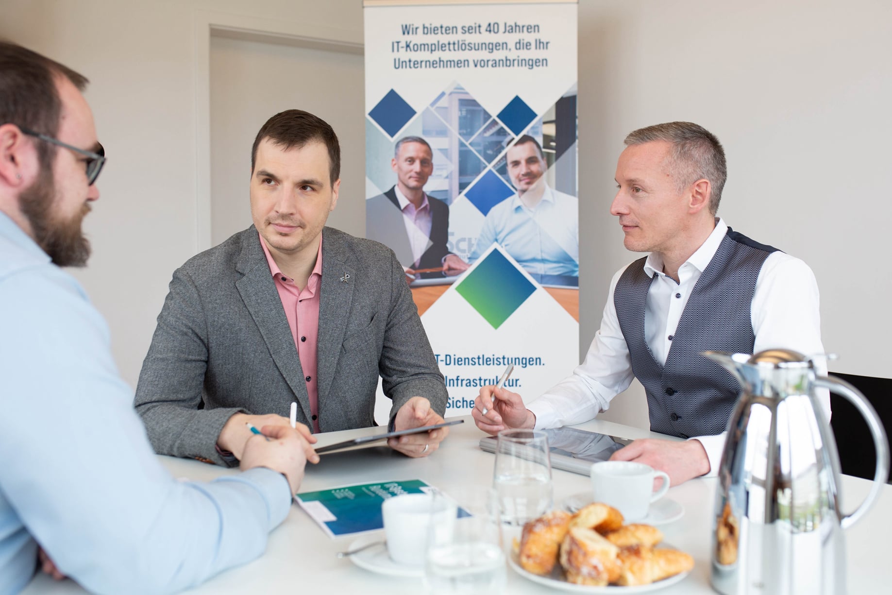 Adrian Barthelund Matthias Hümmer beraten einen Kunden im Besprechungsraum